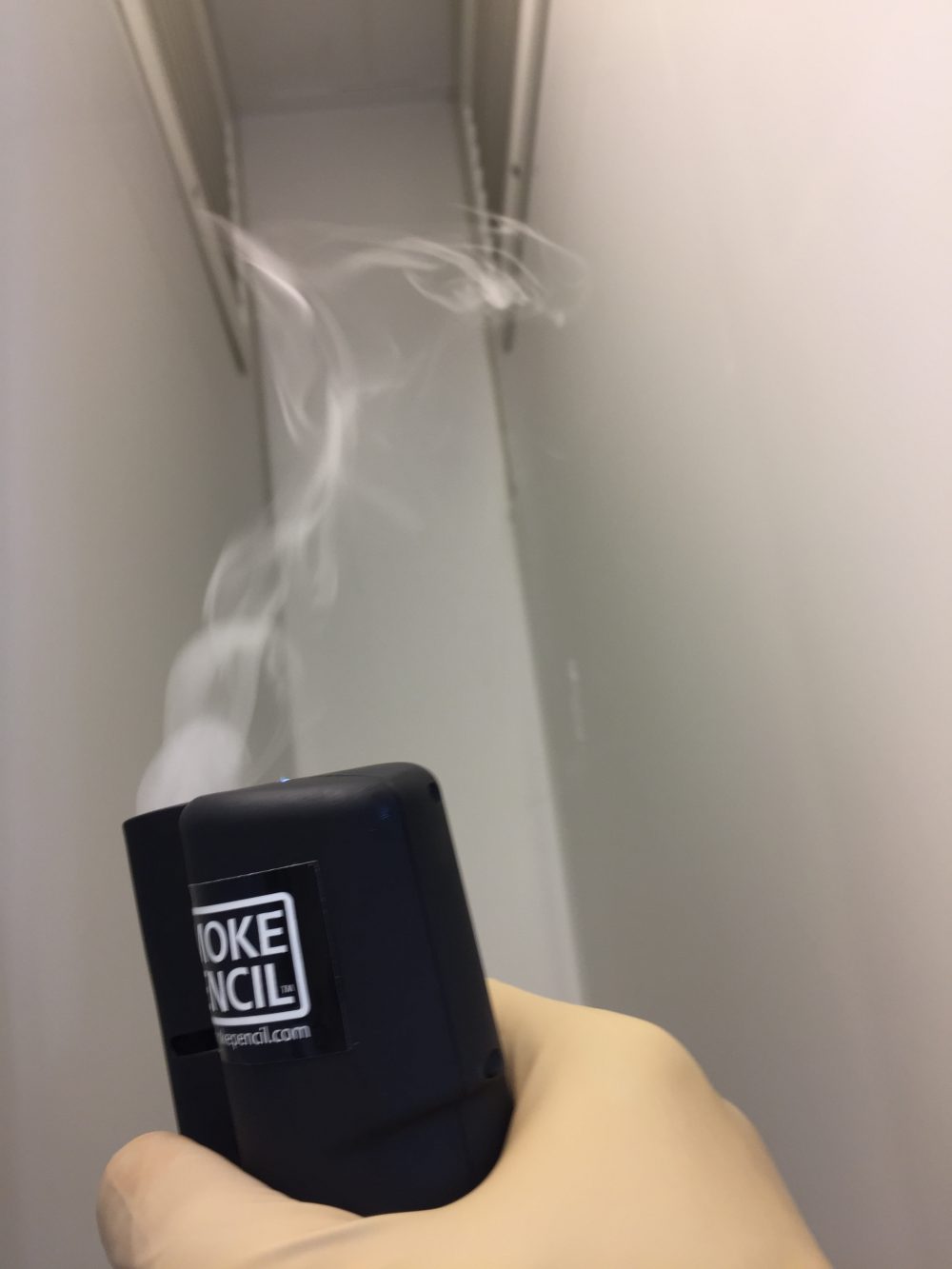Showing man holding smoke pecil testing into application on vents